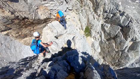 a girl and a boy mountaineer climbing in very high rocks un peaks of europe