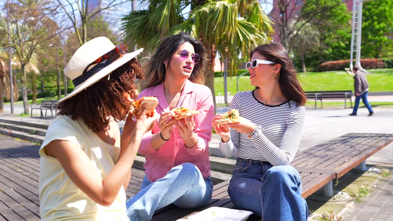 Three Women Enjoying Pizza Outdoors