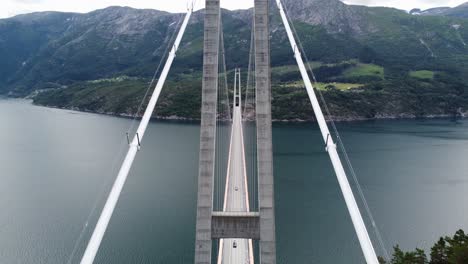 antena en movimiento hacia arriba con vista panorámica ower hardanger bridge - pasando cerca de los cables que sujetan el puente - puente colgante masivo noruega