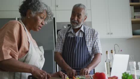 Happy-african-american-senior-couple-cooking-and-talking-together