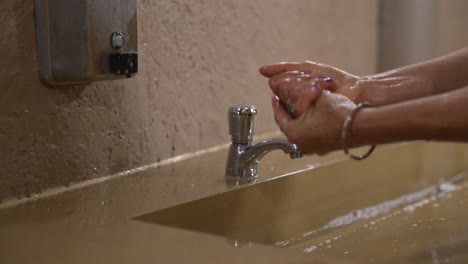 Woman-washing-her-hands-in-public-restroom-area