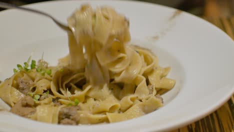 using fork to eat a plate of italian pasta with cheese food in dinner time