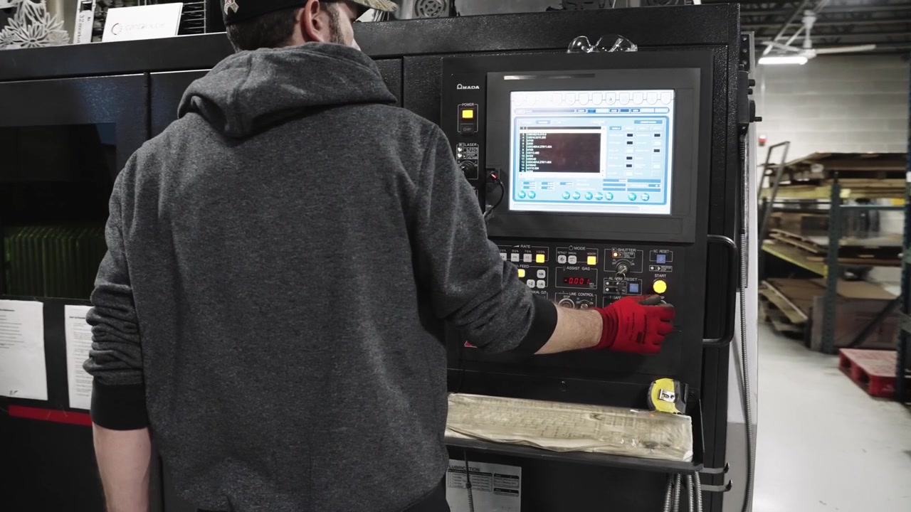 Slow motion, blue collar worker operating industrial laser cutter in a factory