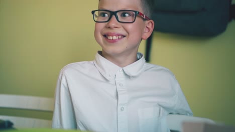 boy-takes-hotdog-from-plate-opposite-friend-at-white-table