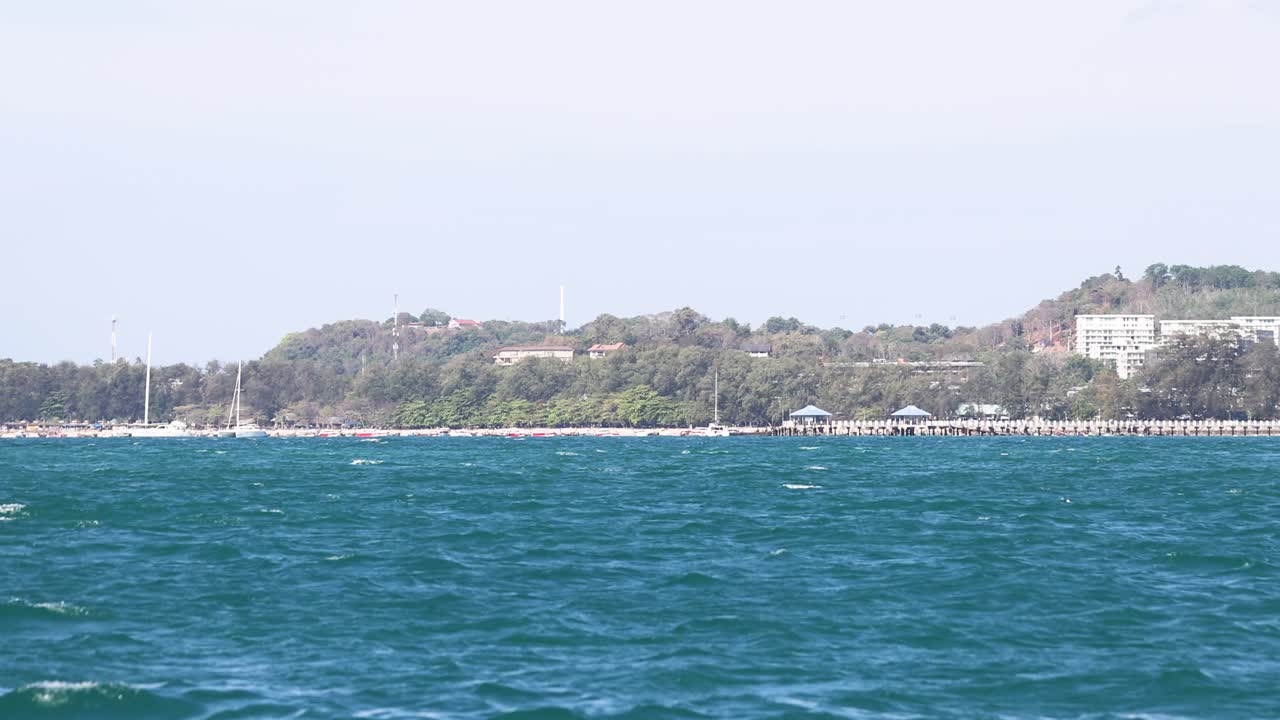 울창한 언덕과 은 하늘을 가진 조용한 바다 장면, 태국의 푸켓에서 움직이는 관점에서 포착되었습니다.