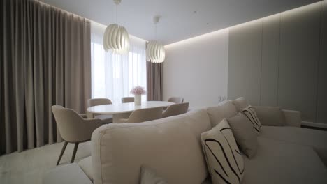 modern living room interior design and decoration with white sofa in living area, dining table and wooden chairs, kitchen counter and cabinets. 4k video 3d rendering apartment room with balcony