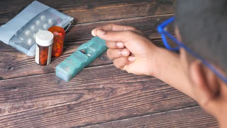 hombre organizando su medicación diaria con un organizador de pastillas