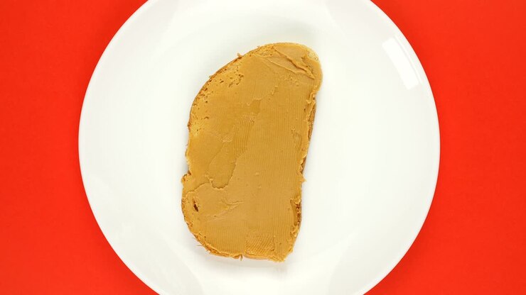 Plate of peanut butter sandwich is slowly rotating on red background.