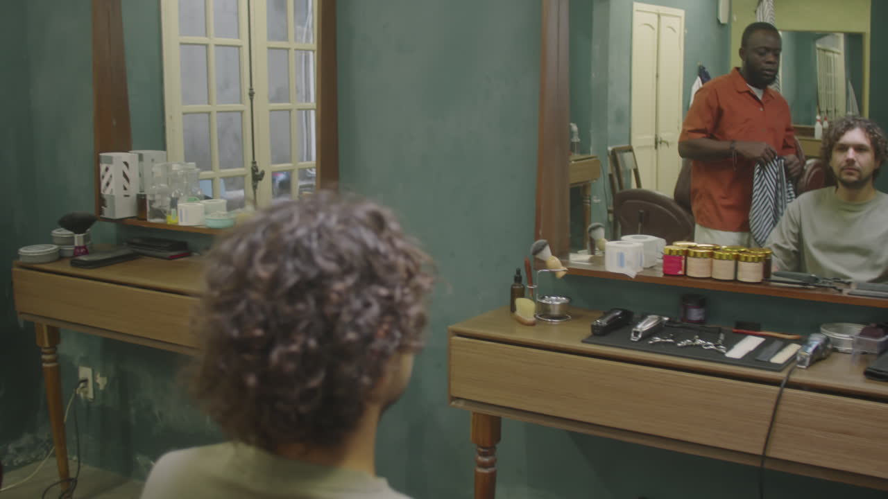 Barber Putting Hairdressing Cape on Male Client