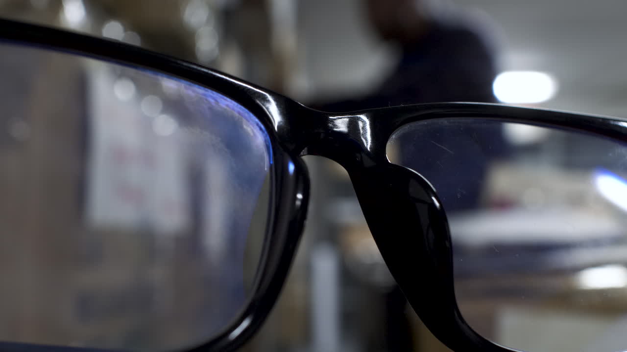 vista de cerca de gafas de montura negra con fondo bokeh de un hombre buscando en los estantes