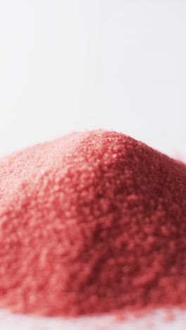 vertical video of close up of heap of red sand grains and copy space on white background
