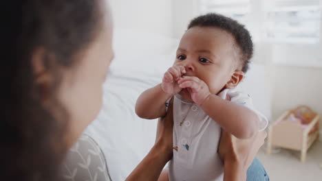 Mother-Cuddling-And-Playing-With-Baby-Son-In-Nursery-At-Home