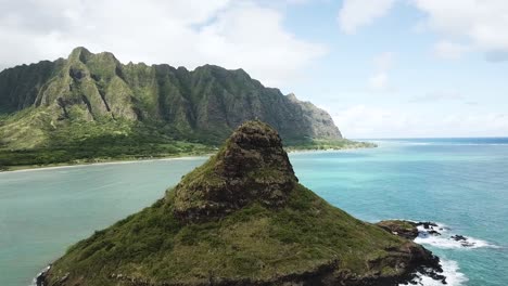 drone shot approaching chinaman's hat with the kualoa mountain range in the background