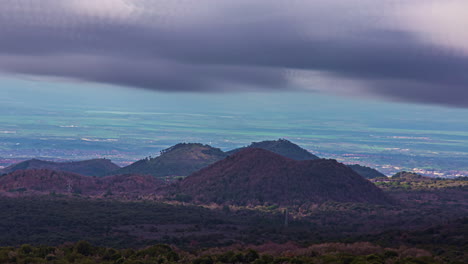 Panoramic-view-of-the-active-volcano-Etna,-Sicily,-Italy-with-extinct-craters-on-the-slope,-traces-of-volcanic-activity-on-a-cloudy-day-with-dark-cloud-movement-in-timelapse-over-the-mountain