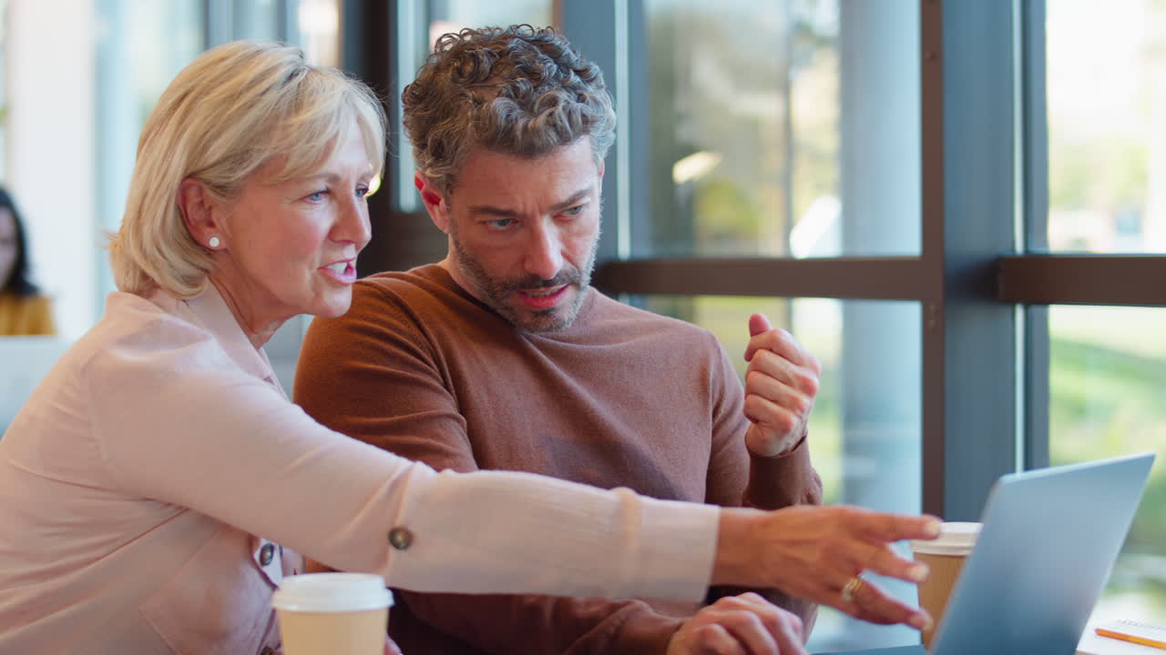 hombre de negocios maduro con una colega que se reúne en un escritorio con una computadora portátil