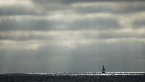 a lonely sailboat on a voyage during dark skies and stormy weather in the vast ocean