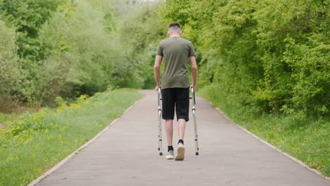 joven con muletas caminando en un parque