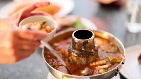 ladling soup into a bowl at a table