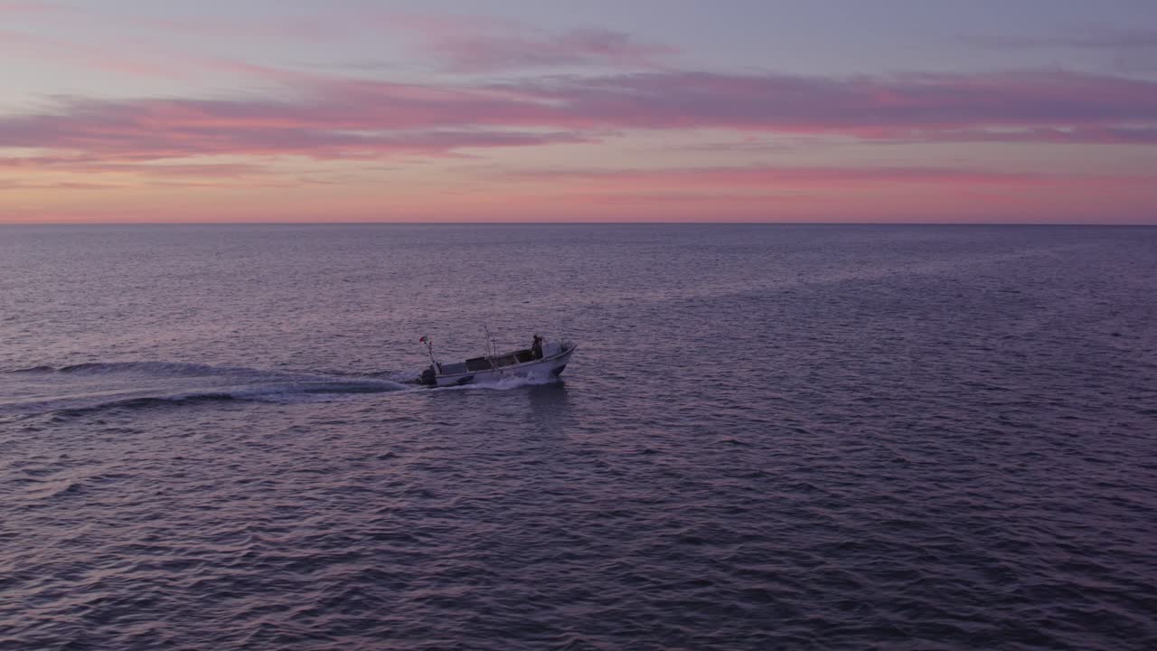 작은 보트가 해가 뜨면 알부페이라 근처의 대서양을 항해하고 있습니다.