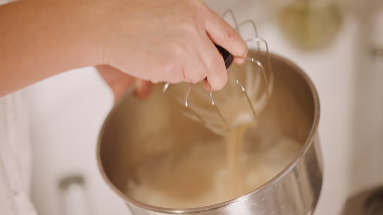 Famiglia che mescola a mano il ripieno della torta di zucca, la nonna insegna la tecnica di sbattitura lenta mentre tramanda una ricetta di famiglia, versando il ripieno setoso in una ciotola di metallo, una scena di cucina calda e nostalgica.