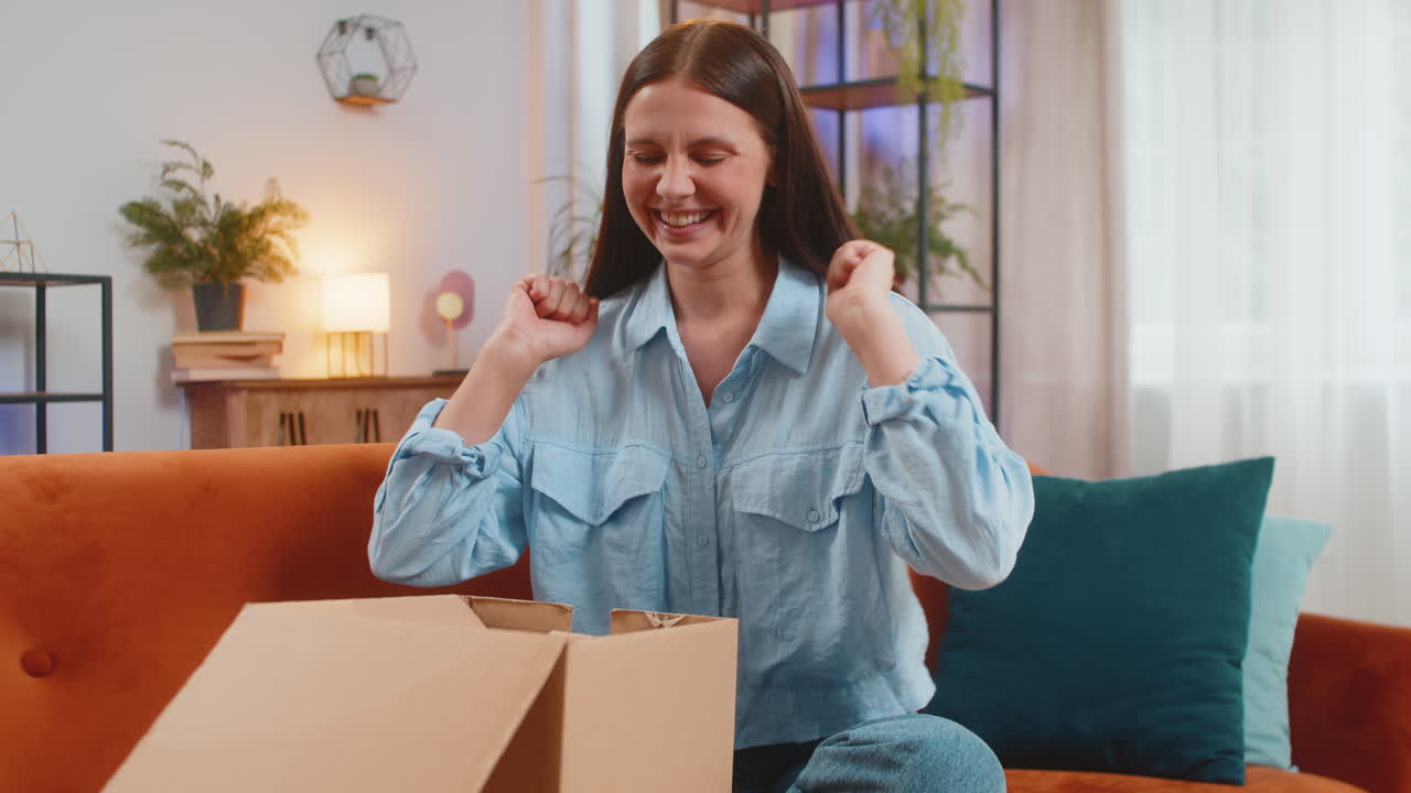 Happy woman girl shopper unpacking cardboard box delivery parcel online shopping purchase at home