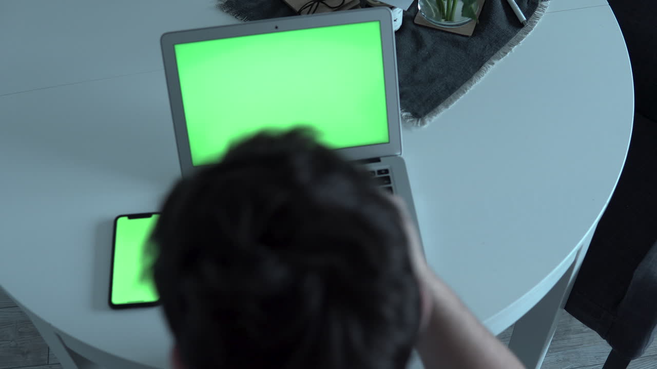 Man working with laptop and mobile phone at home office, green screen, eyeglasses removal and retraction for cases