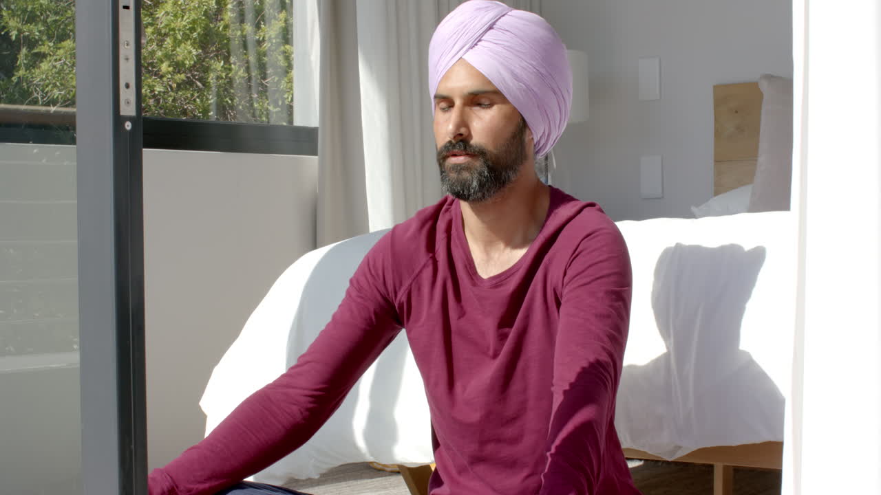 Meditating at home, man in turban sitting cross-legged on floor