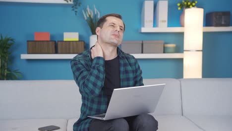 hombre que usa computadora portátil en casa tiene un dolor en el cuello, duele, tiene dolores en las articulaciones.