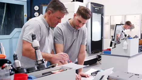 engineer showing apprentice how use cad software on laptop