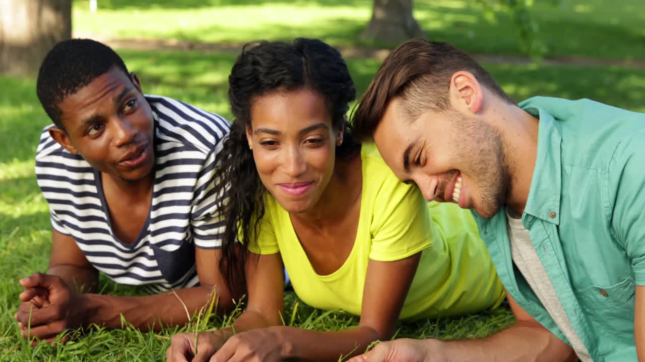 Amici sorridenti che chiacchierano sdraiati sull'erba