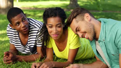 smiling friends chatting and lying on the grass