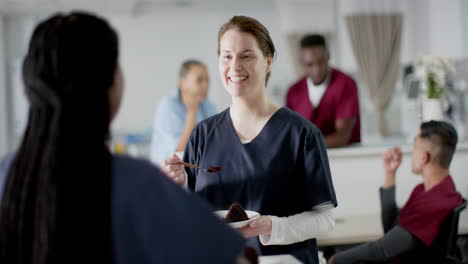 Diverse-male-and-female-doctors-eating-birthday-cake-at-reception-desk-at-hospital,-slow-motion