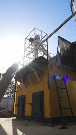 modern constructions on a factory outdoors. industrial equipment near grain elevators. exterior of a modern plant for agribusiness. vertical video