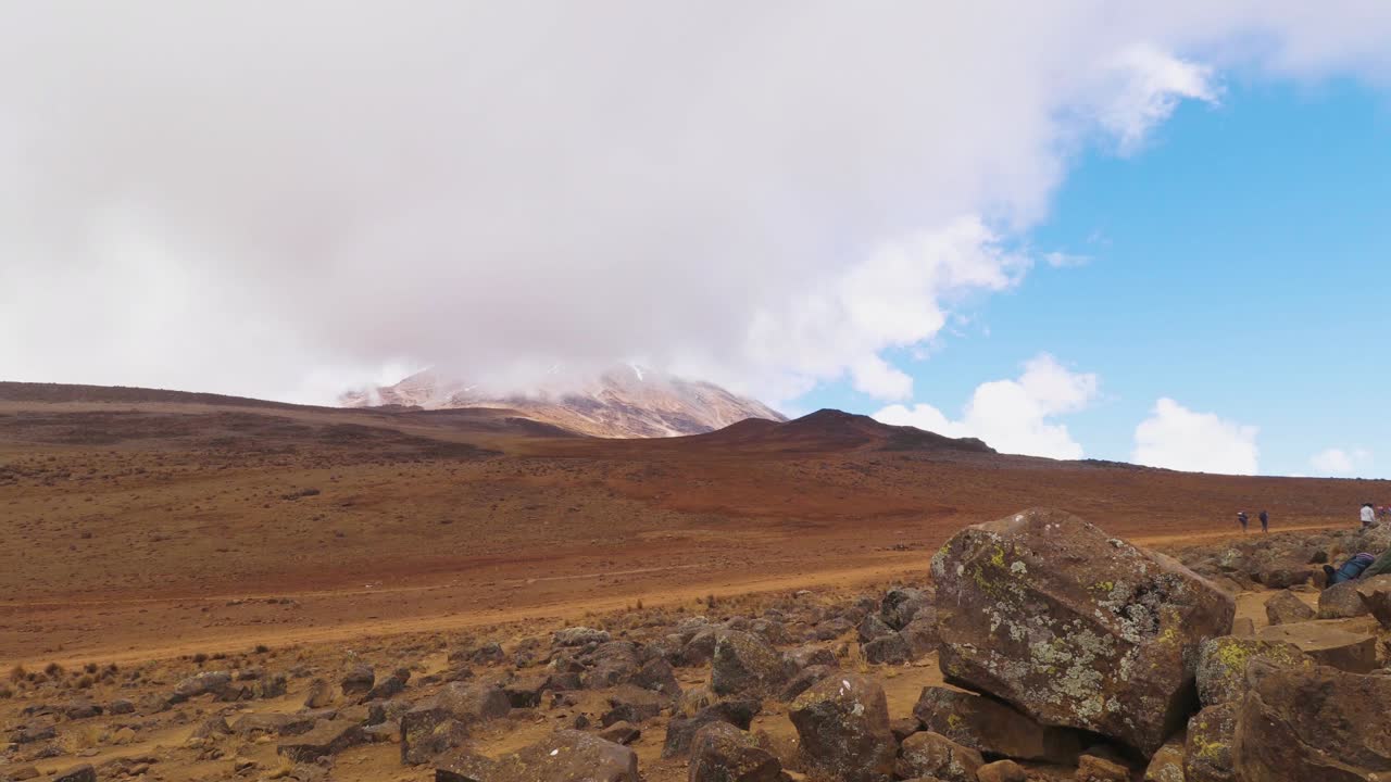 toma de lapso de tiempo de personas caminando por el sendero uhuru, hacia la cumbre del monte kilimanjaro, en un día brumoso y soleado, en tanzania, áfrica