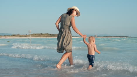 woman enjoying family weekend at seaside. mother and son walking in seashore.