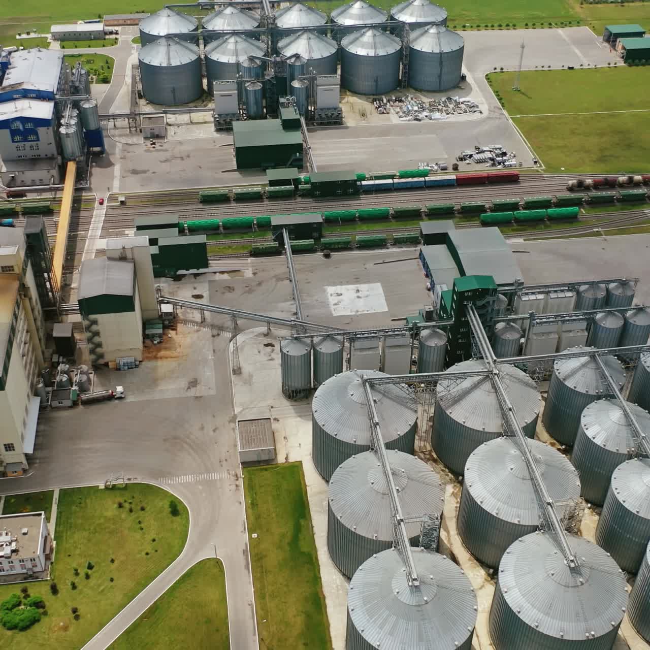 Farmland with grain granary. Flight over huge agricultural zone with steel elevators. Silos for harvest on modern factory in the field. Aerial view.