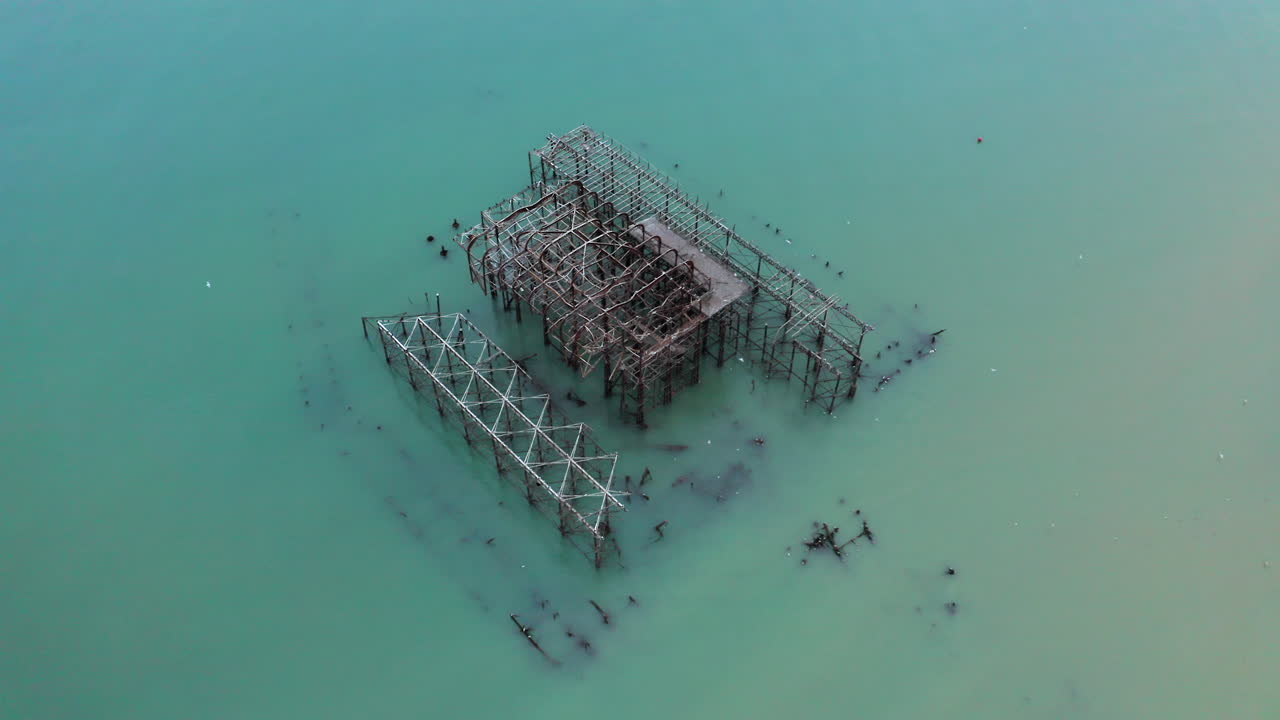 A pulling away aerial shot of west pier ruin in Brighton with seagulls flying about