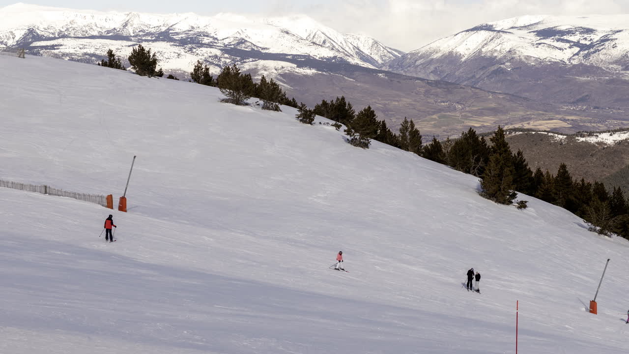 Sciatori che scendono un pendio montano innevato in una località sciistica