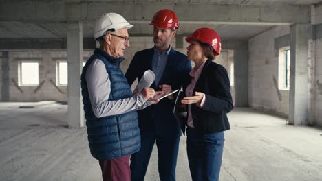 Static-wide-shot--footage-of-group-of--caucasian-engineers-and-investors-standing-and-discussing-on-construction-site.