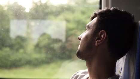 Profile-of-the-handsome-dark-haired-man-thoughtfully-looking-at-the-window.-Travels-by-train.-Looking-at-camera.-Excited-about-journey.-Smiling.-Side-view