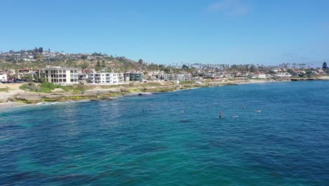 4K-Aerial-Drone-Video:-Flying-surfers-towards-homes-on-Sunny-September-Day,-Ocean-and-Waves-Crashing-on-Beach---2023