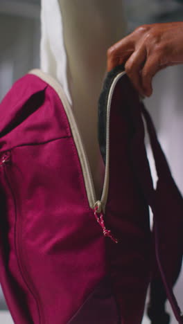 vertical video close up of woman at gym for exercise class opening zip of sports bag and taking out towel and water bottle