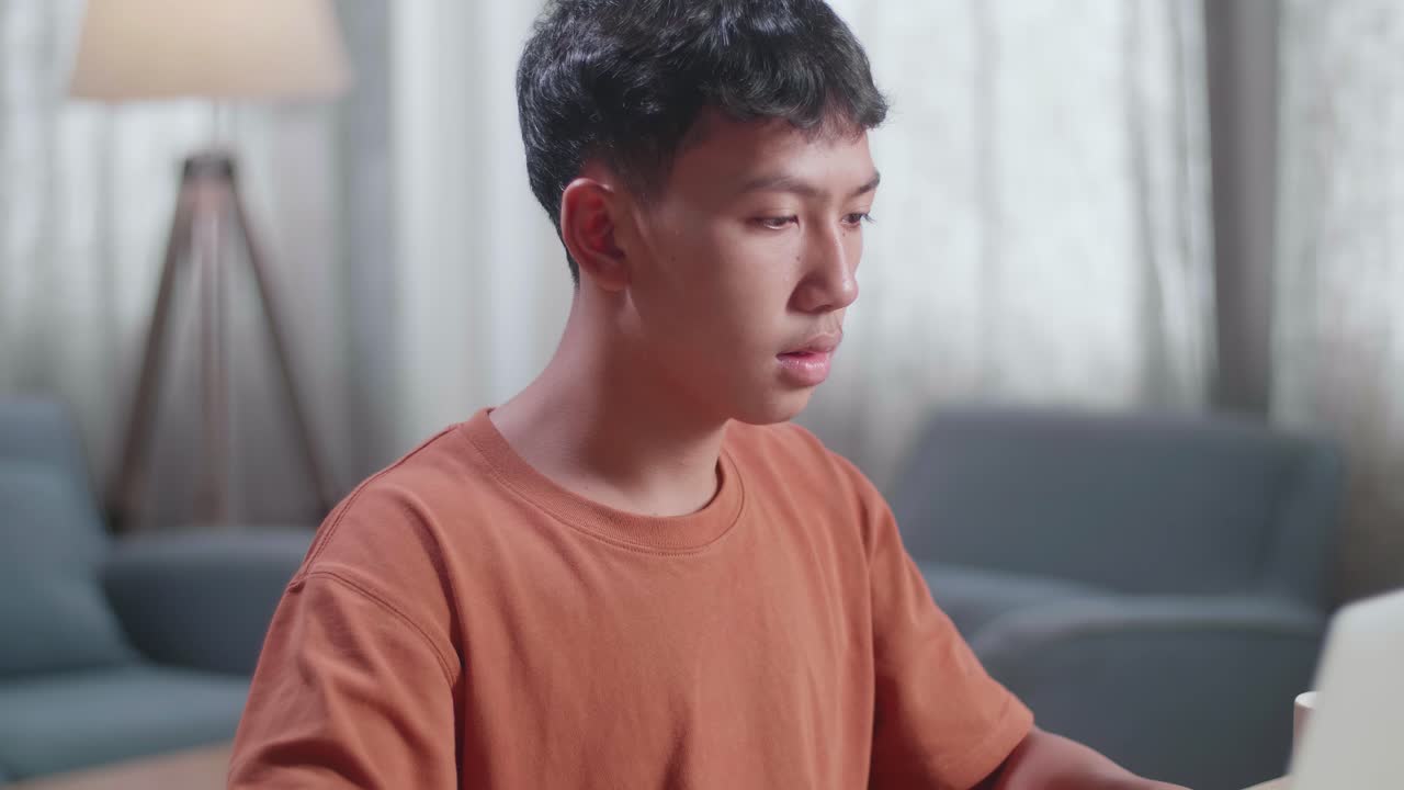 아시안 소년 신발 디자이너가 집에서 노트북으로 작업하는 동안 생각하고 있습니다.