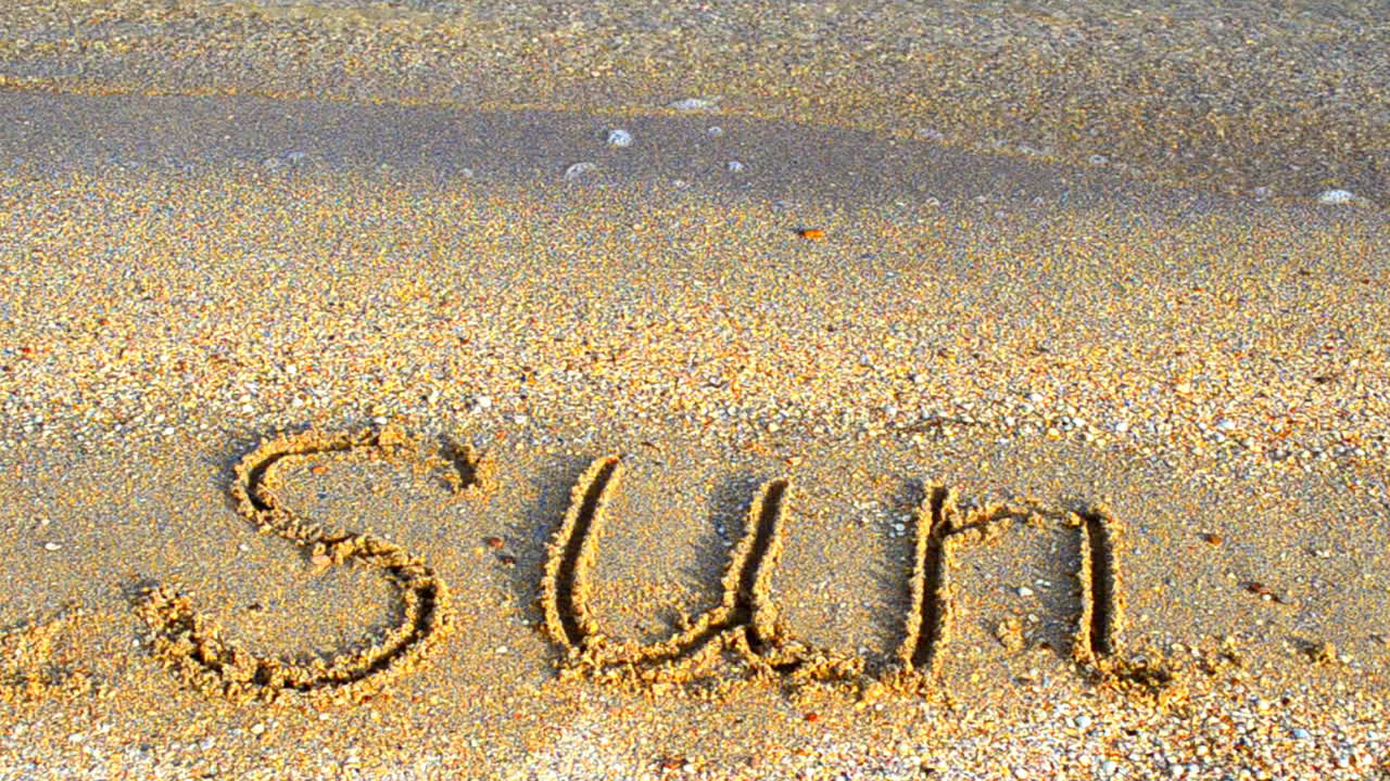 Solindskrift i sandet, stranden. Solskinsdag, afslapning
