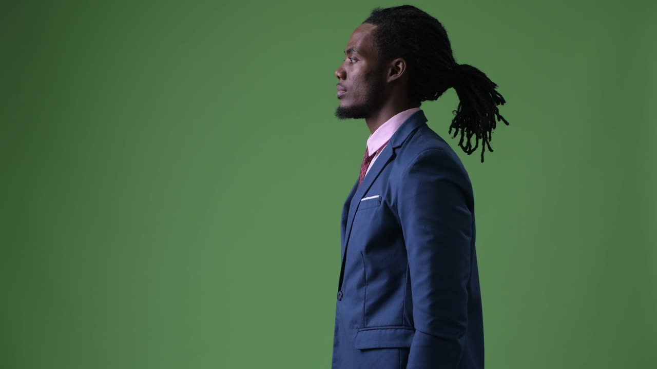 Young handsome African businessman with dreadlocks against green background