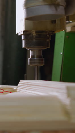 primer plano de una máquina cnc trabajando en madera contrachapada, resaltado por la iluminación del taller, la dispersión de aserradura