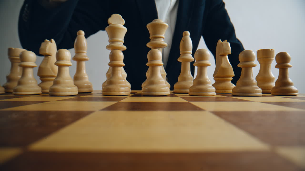 Chess player hand making first move with white pawn on chessboard alone closeup