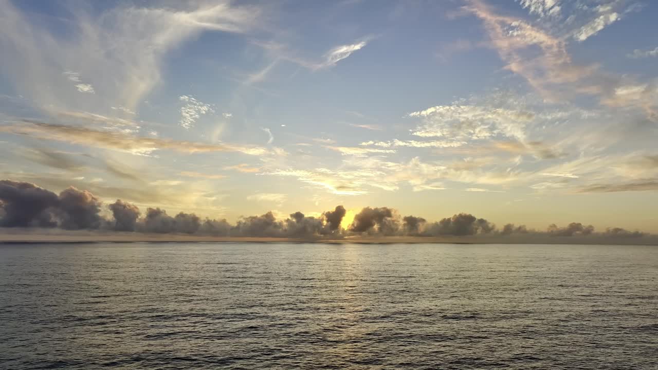 vistas tranquilas y serenas del agua del océano que refleja la suave luz del atardecer con nubes esponjosas en el horizonte del cielo azul