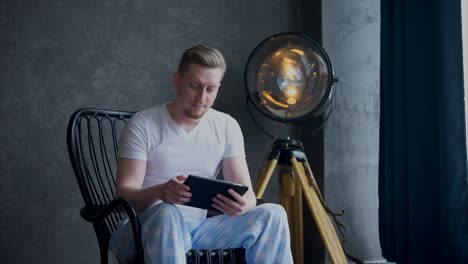 man reading on tablet in a chair