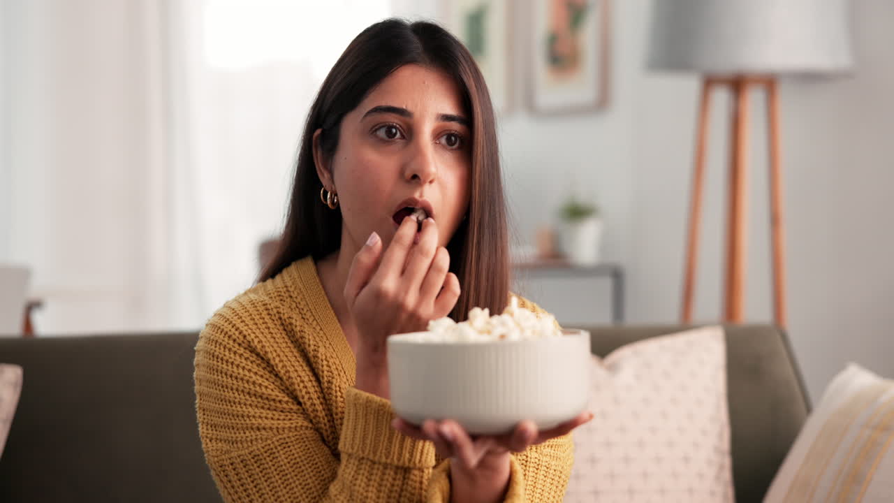 Donna che mangia popcorn mentre guarda la TV